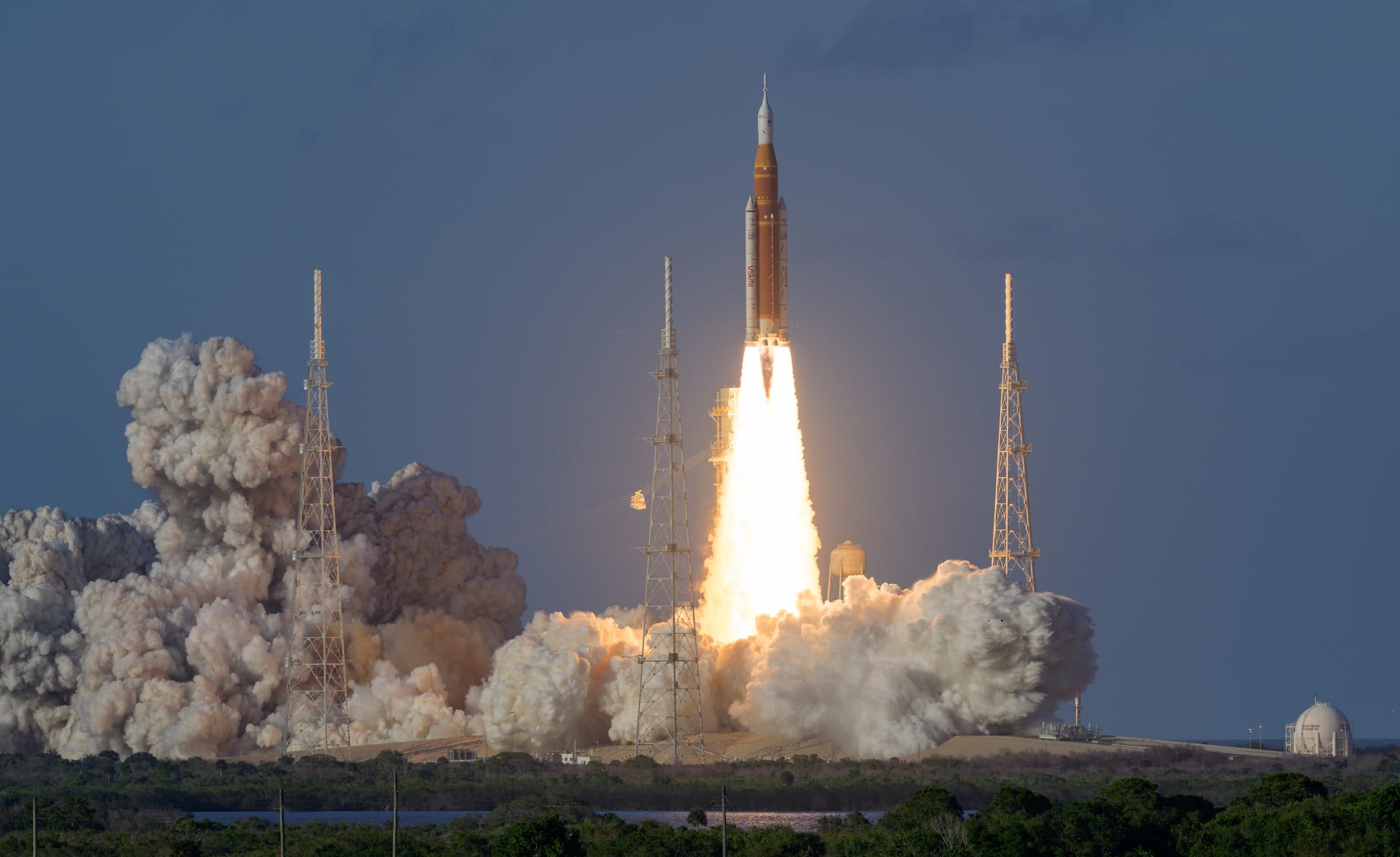 Despegue de un cohete espacial pesado desde su plataforma, con una gran columna de fuego y humo.
